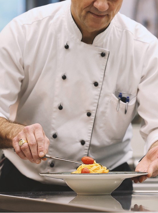 Cityhotel — a chef plating spaghetti with cherry tomatoes