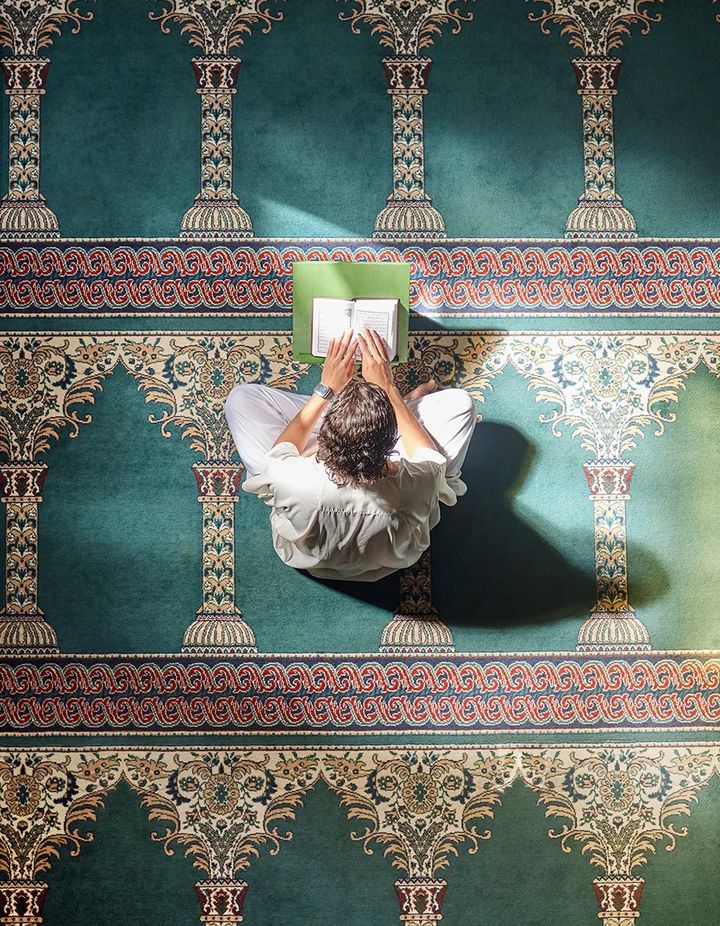 En-Nur — a person reading on a mosque prayer carpet, seen from above