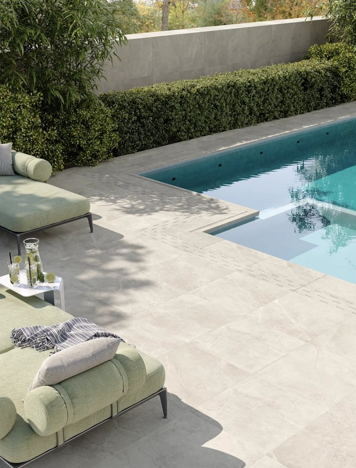 Jetonikeramika — light stone-look tiles around a swimming pool, with green garden loungers