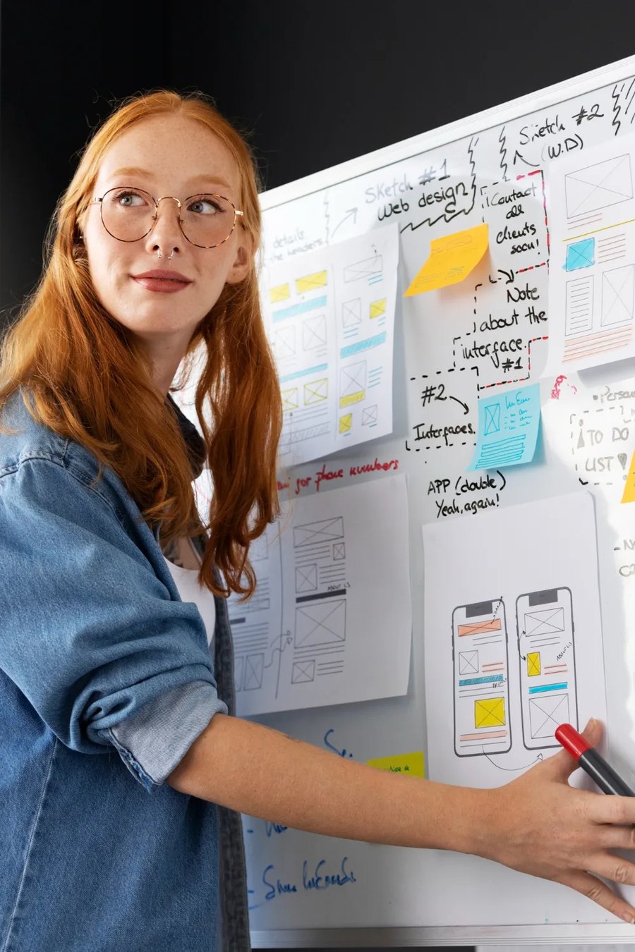 Monun AG — a person pointing at website and app wireframes pinned to a whiteboard