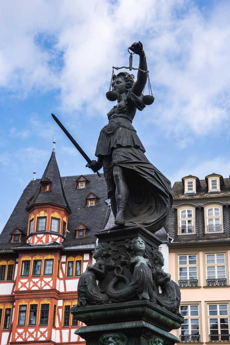 Kanzlei Pilatushof — a statue of Justice with her scales and sword in front of old town houses