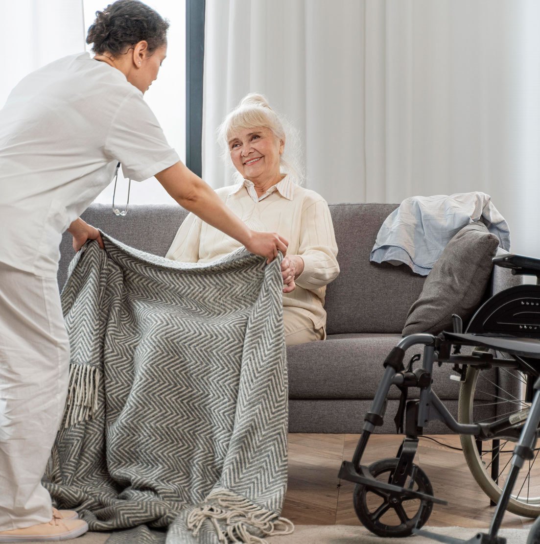 Spitex Schwab AG — a carer laying a blanket over an older woman on her sofa at home